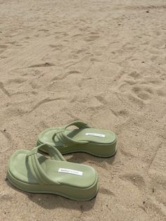 a pair of green slippers laying in the sand