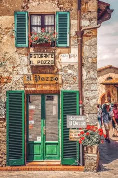 an old building with green shutters and flowers in the window boxes on the outside