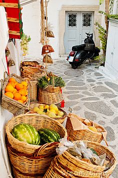 several wicker baskets filled with fruits and vegetables on the side of a building next to a scooter