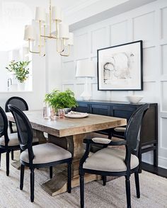 a dining room table with four chairs and a potted plant in the corner on top