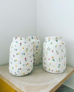 two white vases sitting on top of a wooden table next to each other in a room