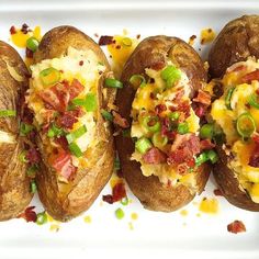 four loaded baked potatoes on a white plate