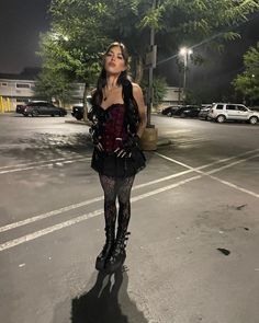 a woman standing in the middle of an empty parking lot at night with her eyes closed