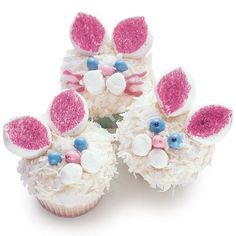 four cupcakes with pink and white frosting decorated like bunny's ears