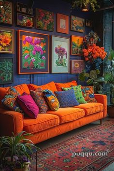 an orange couch with many colorful pillows on it in front of pictures and plants hanging on the wall