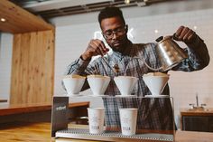 a man pours coffee into cups from a machine