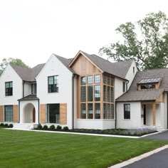 a large white house with lots of windows on it's sides and grass in the front yard