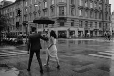 a man and woman walking in the rain with an umbrella