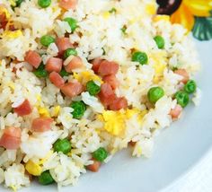 rice and peas are mixed together on a white plate with flowers in the back ground