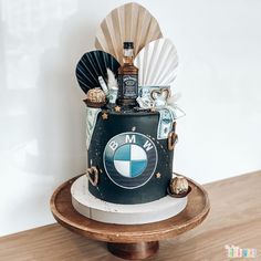 a birthday cake decorated with an image of a bmw bottle and other items on a wooden stand