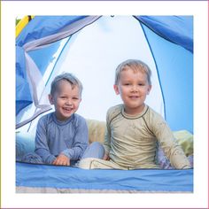 two young boys are sitting in a tent