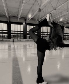 a woman in black leotard doing a handstand on an ice rink