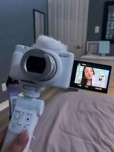 a person is holding up a video camera to take a picture in the bed room