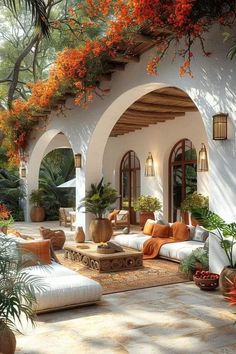 an outdoor living area with couches and potted plants on the side of it