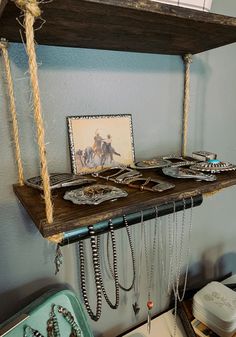 a shelf that has some necklaces on it and two pictures hanging from the top