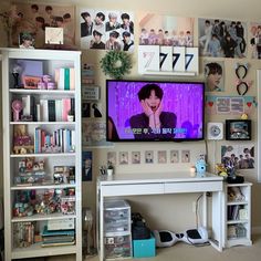 a flat screen tv sitting on top of a white shelf next to a bookcase