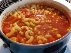 a blue pot filled with pasta and tomato soup on top of a gas burner