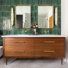 a bathroom vanity with two mirrors above it and a white toilet in the back ground