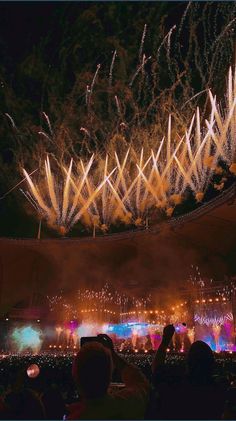 fireworks are lit up in the night sky above an arena with people watching from their seats