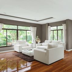 a living room filled with white furniture and windows