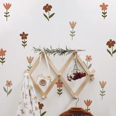 a white wall with flowers and plants on it, next to a wooden frame hanging from the wall