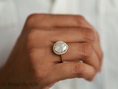 a woman's hand holding a ring with a pearl and diamond center on it