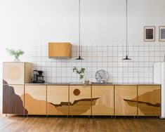 a kitchen with wooden cabinets and white tiled walls, along with a wood flooring