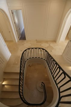 an aerial view of a spiral staircase in a house with white walls and beige flooring