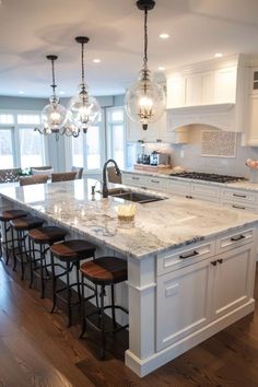 a large kitchen island with marble counter tops and stools in front of the sink