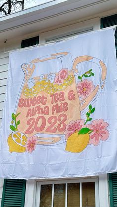 a banner hanging from the side of a building with flowers and lemons on it