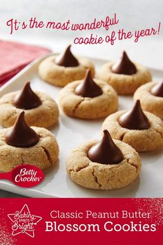 some cookies are on a white plate and have chocolate frosting on them with the words, it's the most wonderful cake of the year classic peanut butter blossom cookies