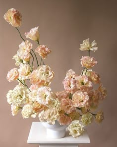 a white vase filled with lots of pink and white flowers