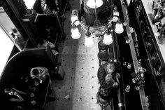 black and white photograph of people sitting at tables in a restaurant with chandeliers