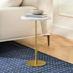 a table with a book on it in front of a couch and chair, next to a rug