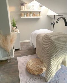 a white bed sitting under a slanted ceiling next to a wooden floor covered in blankets