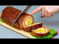 a person cutting into a meatloaf with an egg in the center