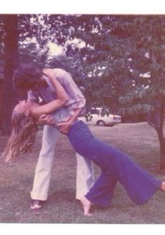 two people standing in the grass with their arms around each other