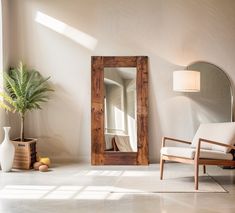 a room with a chair, mirror and potted plant on the floor in front of it