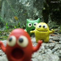 three little toy monsters are standing on the ground with their mouths open and eyes wide