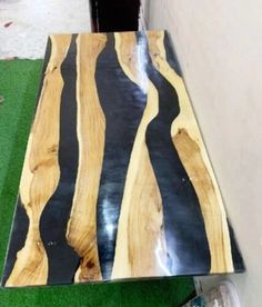 a table made out of wood with black and white stripes on it, sitting in the grass