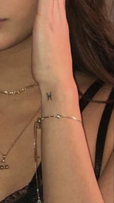 a woman holding her hand up to her face with a cross tattoo on her left arm