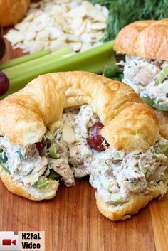 two croissants filled with chicken salad on top of a wooden cutting board