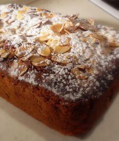 a loaf of bread covered in powdered sugar and almonds on a white plate