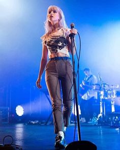 a woman standing on top of a stage with a microphone in her hand and another person behind her