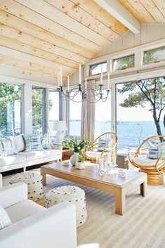 a living room filled with lots of furniture and large windows overlooking the water's edge