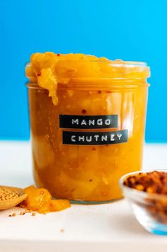 a glass jar filled with mango chutney next to a cookie