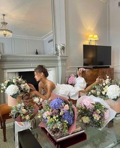 two brides sitting in chairs with bouquets on the coffee table, and one is looking at her phone