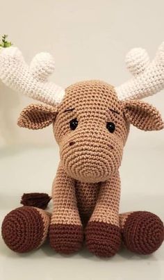 a crocheted moose sitting on the ground with its legs crossed and it's eyes wide open