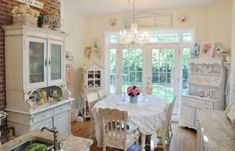 an old fashioned kitchen and dining room are decorated in white with pink flowers on the table