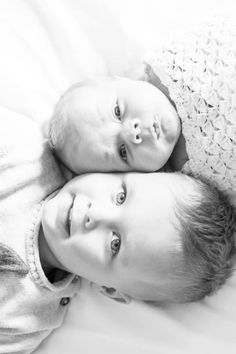 two young children laying on top of each other in black and white photo taken by the photographer